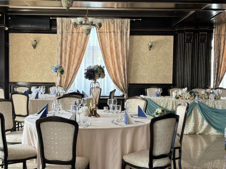 Sala de evenimente cu mese rotunde si decor albastru-petrol la masa prezidiului